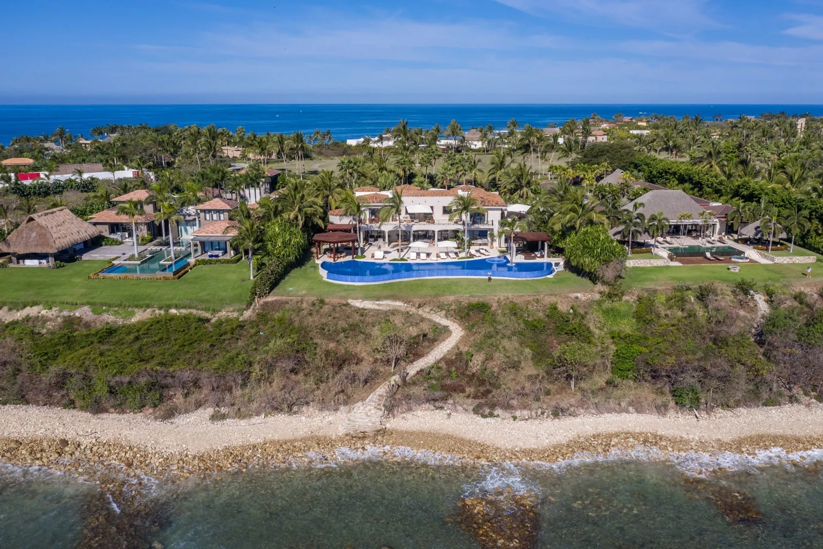 The villa seen from over the water, the lawn running down to the shore