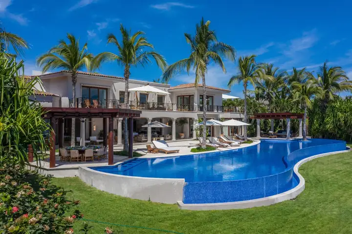 The curving infinity pool between the terrace pergolas and the lawn