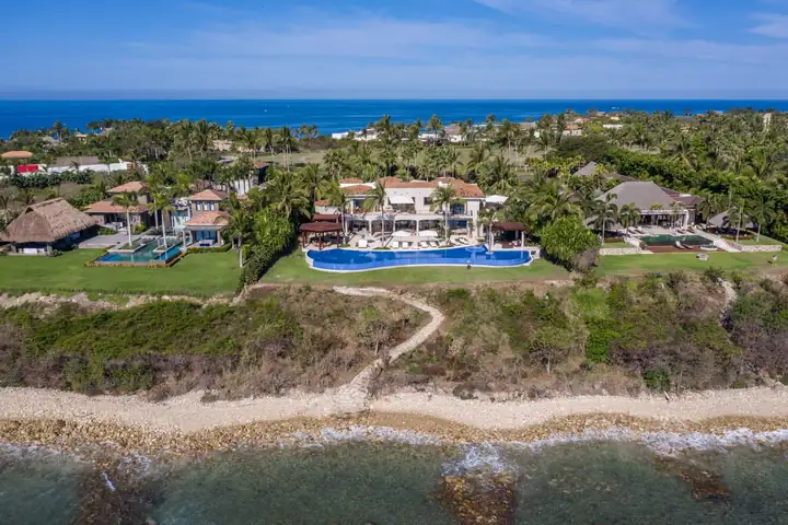The villa seen from over the water, the lawn running down to the shore