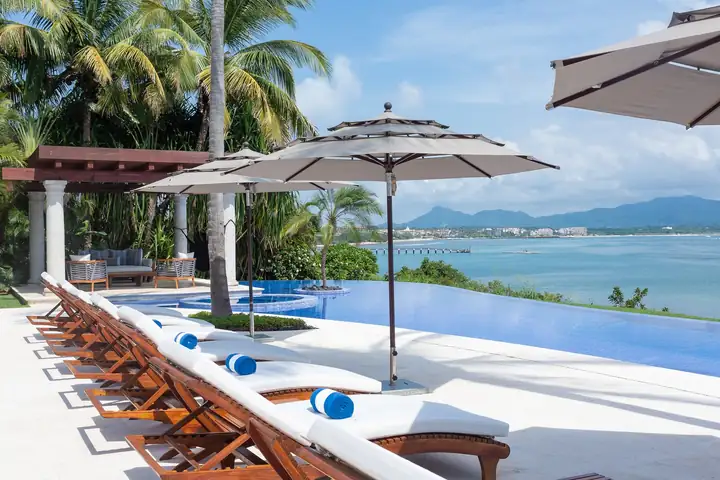 Teak loungers under umbrellas beside the pool