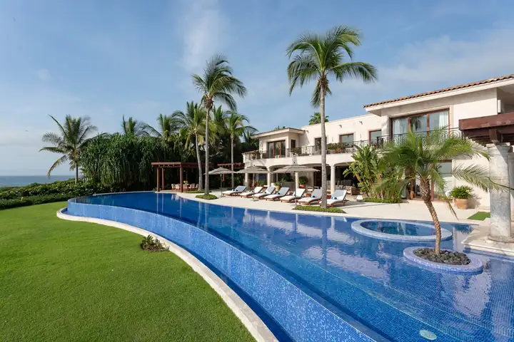 The long blue pool curving along the lawn